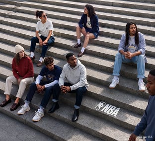 Groupe d'amis assis sur les marches d'un escalier, habillés en NBA