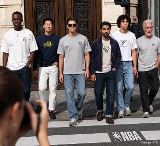 Groupe de personnes en tee-shirts et sweats NBA traversant une rue de Paris
